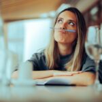 A woman balances a pen on her upper lip.